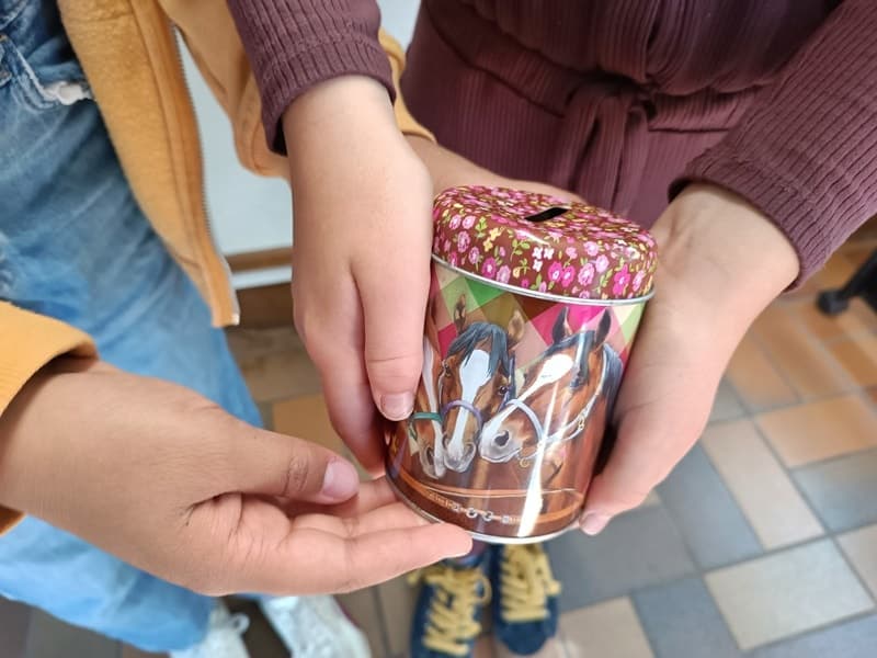 Kinderhände halten eine gefüllte Spendendose